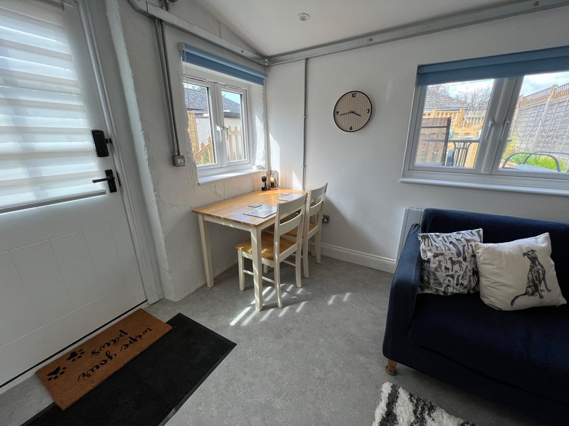 Studio room with small desk, chair, single bed with cushions and natural light from windows