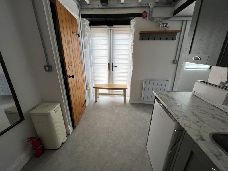 Kitchen with white appliances, marble countertop, wooden door and louvered windows