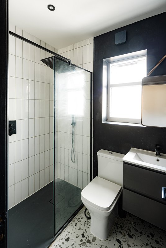 Modern bathroom with walk-in shower, toilet, sink vanity and window