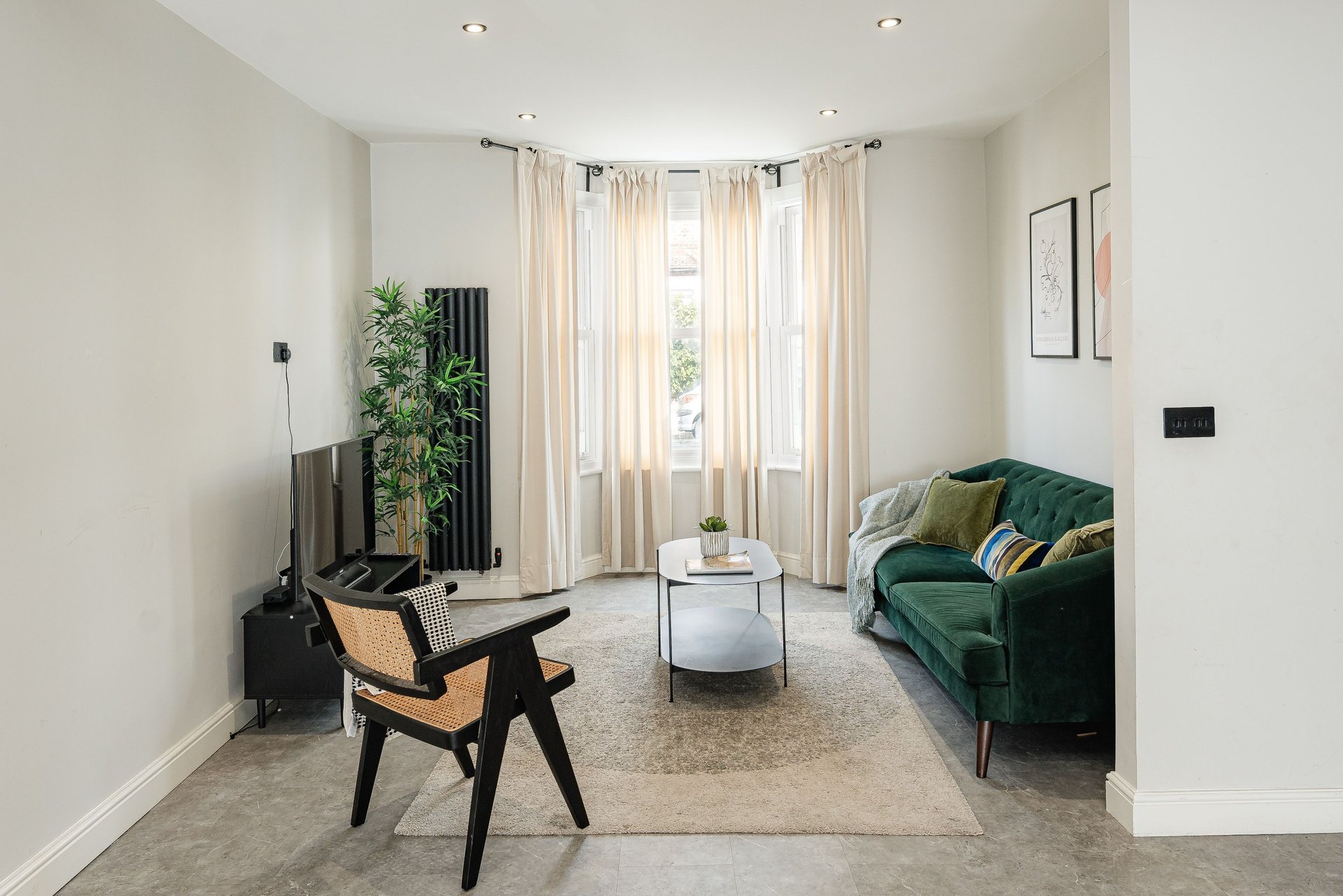 Modern living room with green sofa, wooden chair, coffee table and large windows
