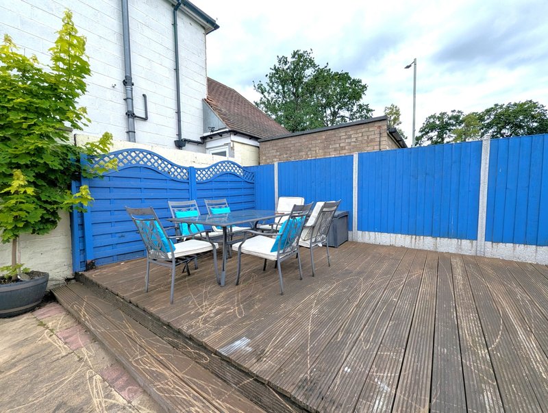 Outdoor deck with blue fence, dining table, chairs and potted plants