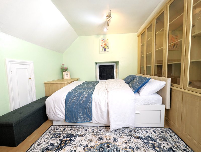 Bedroom with double bed, blue bedding, wooden wardrobe, and patterned rug