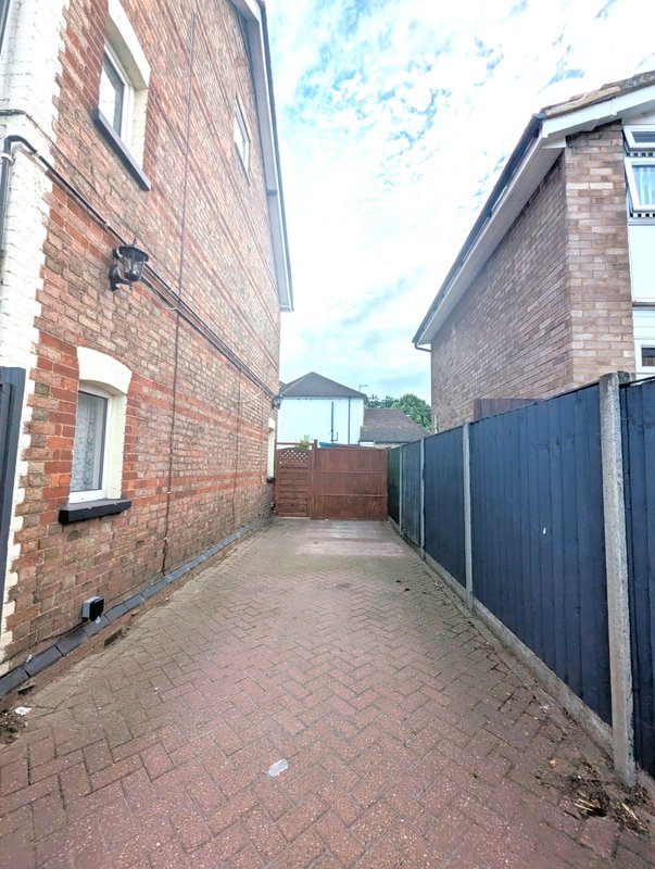 Outdoor brick paved alleyway between two houses with fenced sides
