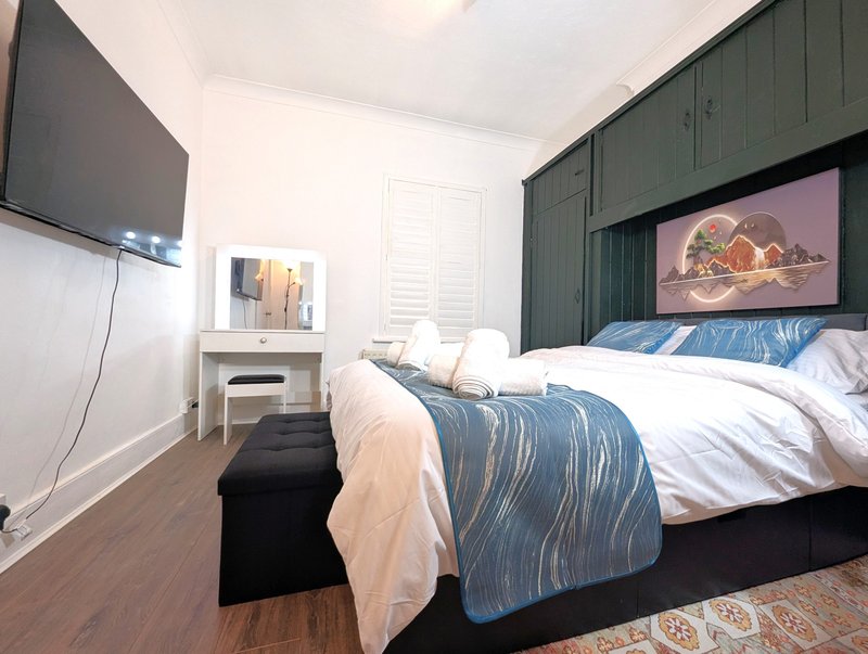 Modern bedroom with double bed, TV, desk, and green-paneled headboard wall