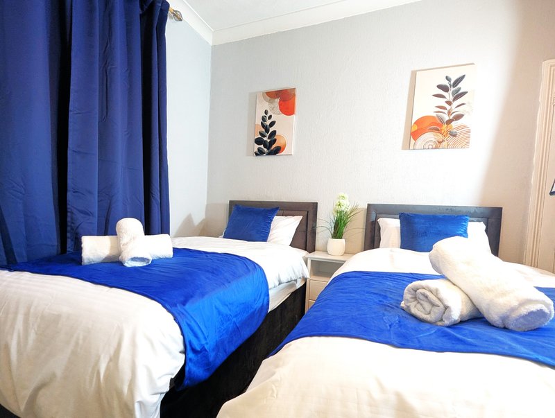 Twin bedroom with blue bedding, white pillows, matching bedside tables and wall art
