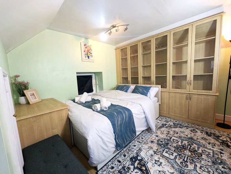 Bedroom with double bed, wooden storage cabinets, fireplace, and patterned rug