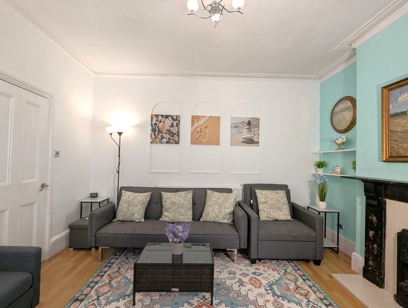 Living room with gray sofa, fireplace, turquoise accent wall and framed artwork