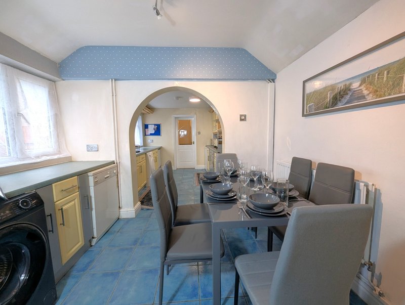 Kitchen-diner with dining table, chairs, washing machine and archway to hallway