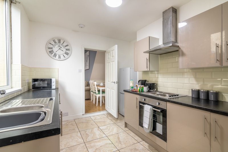 Modern kitchen with cream cabinets, black countertops, built-in oven and extractor hood