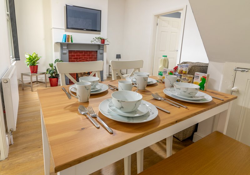 Spacious dining room with wooden table, place settings, fireplace and plants