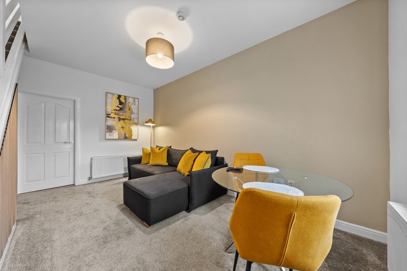 Modern living room with black sofa, yellow armchair, and beige accent wall