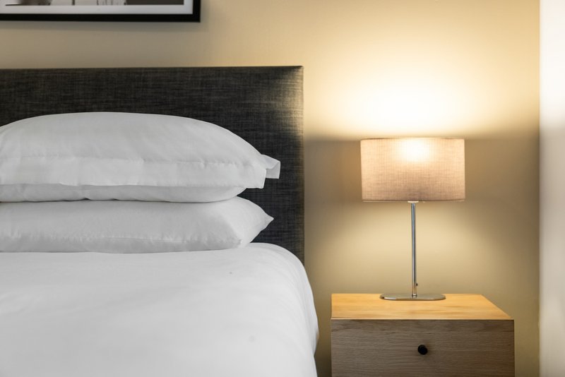 Bedroom with double bed, white bedding, dark headboard and table lamp