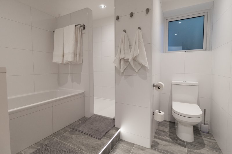 Modern bathroom with walk-in shower, toilet, and towel rails