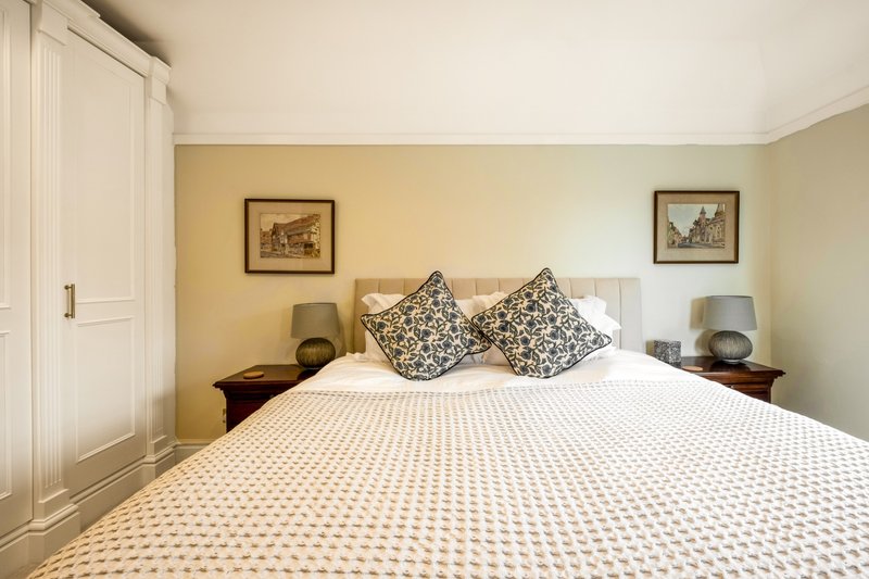 Bedroom with double bed, patterned bedding, decorative pillows, bedside lamps and framed wall art