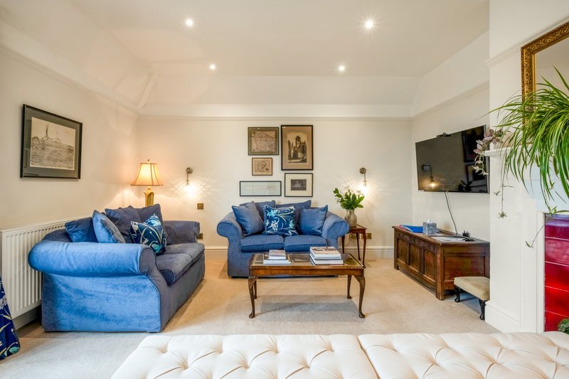 Spacious living room with blue sofas, wooden coffee table, wall art, and mounted TV