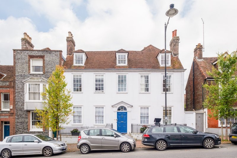 Multi-storey Georgian townhouse with white facade, blue door and parked cars on street