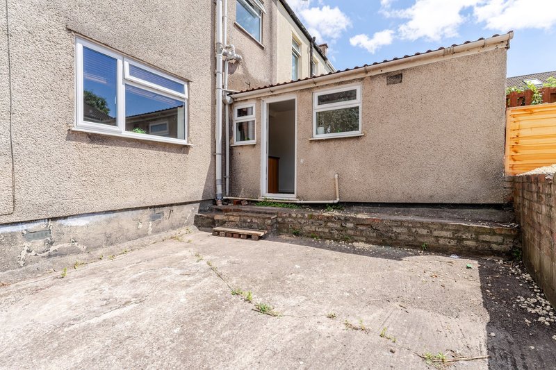 Exterior courtyard with paved ground, stone walls, windows and door entrance