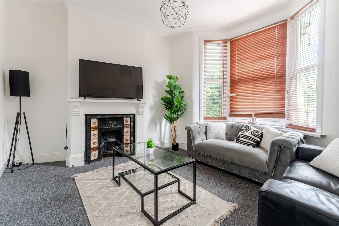 Modern living room with grey sofa, fireplace, TV, geometric pendant light and orange blinds