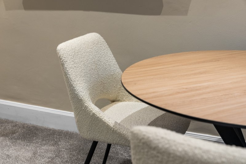 Dining area with wooden round table and upholstered cream chair