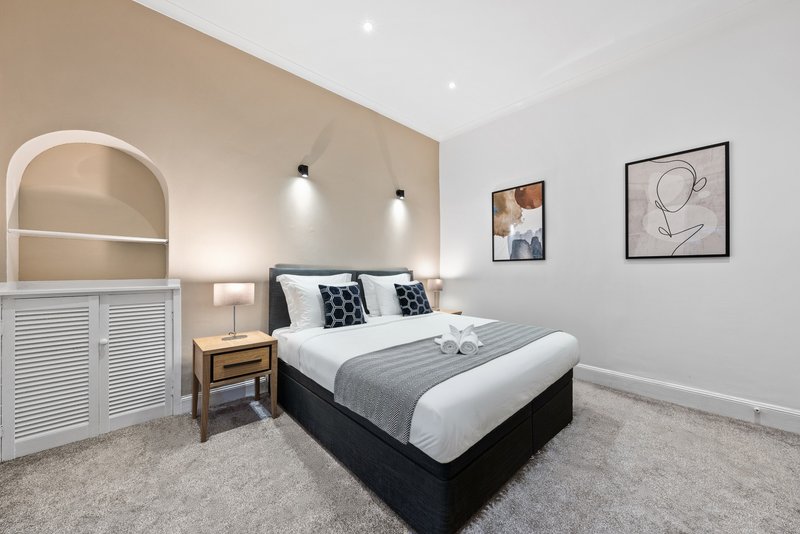 Modern bedroom with double bed, bedside table, wall sconces, and framed artwork
