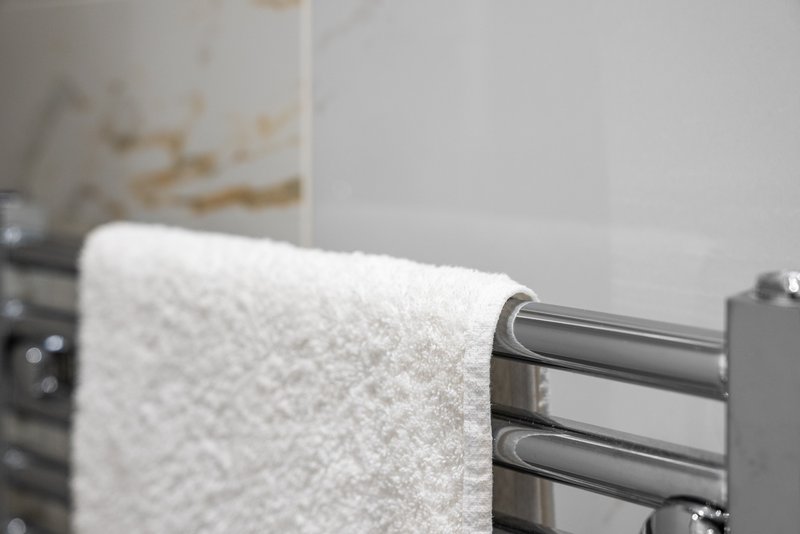 White towel draped on modern heated towel rail in bathroom