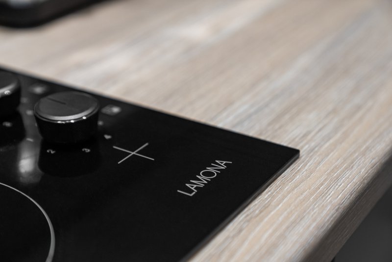 Close-up of black control panel with knobs on light wood surface