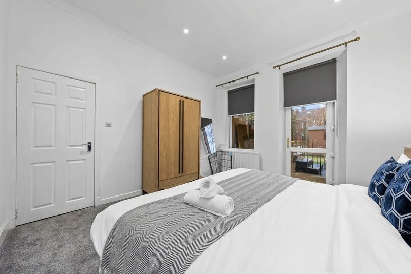 Bright bedroom with double bed, wooden wardrobe, white door and garden views