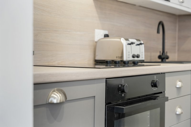 Modern kitchen with cream toaster, kettle, black oven and dark tap