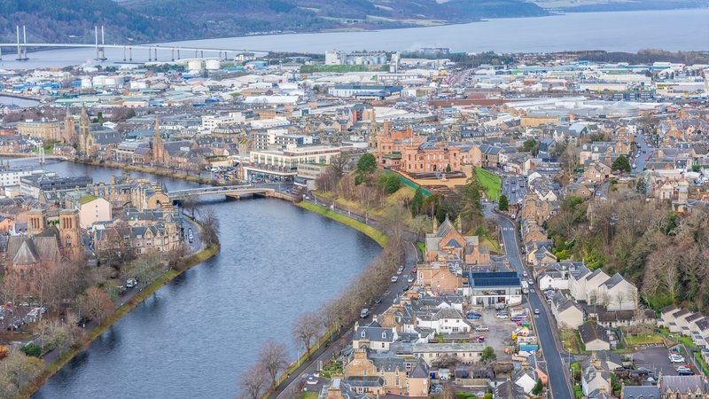 Aerial view of riverside town with historic castle, winding river, and surrounding residential buildings
