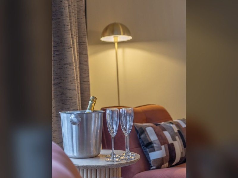 Bedside table with ice bucket, champagne bottle, and two glasses under brass lamp