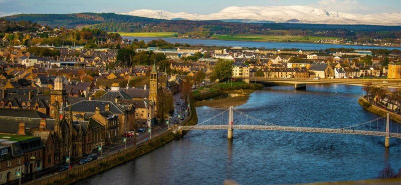 Aerial view of riverside town with historic buildings, bridge, and surrounding countryside landscape