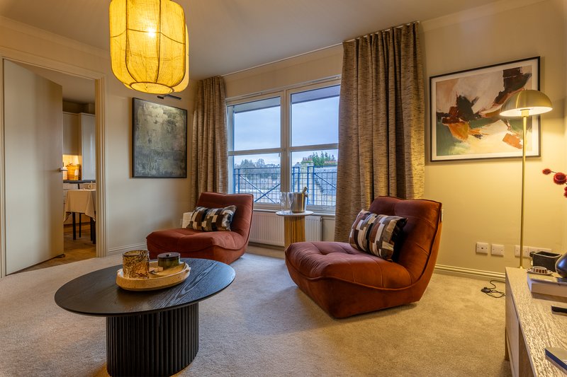 Modern living room with burgundy armchairs, round black coffee table, yellow pendant light and mountain view