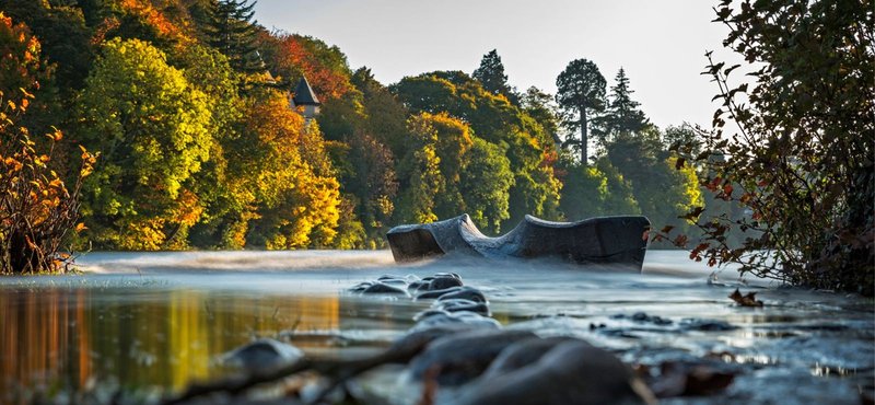 River landscape with autumn trees, rocks and water, natural scenic view