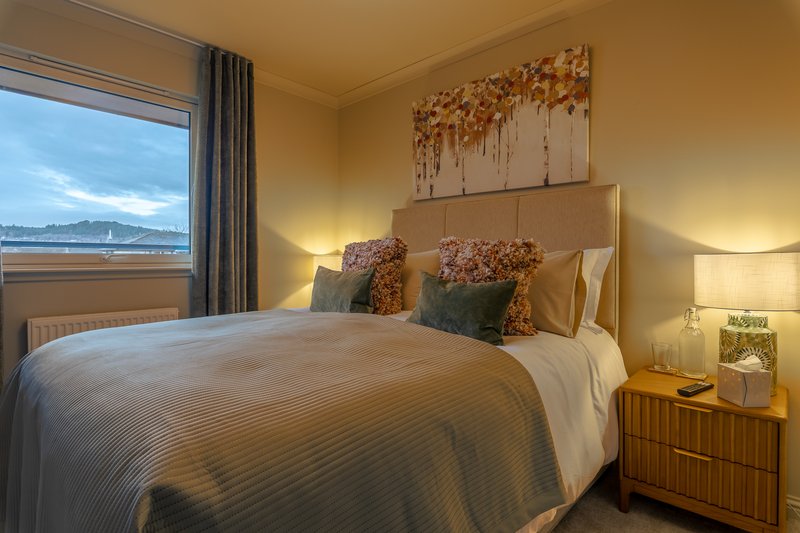 Bedroom with double bed, bedside tables, lamps, and window with water view
