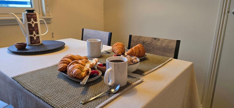 Dining table set with croissants, pastries, coffee and tableware for breakfast service