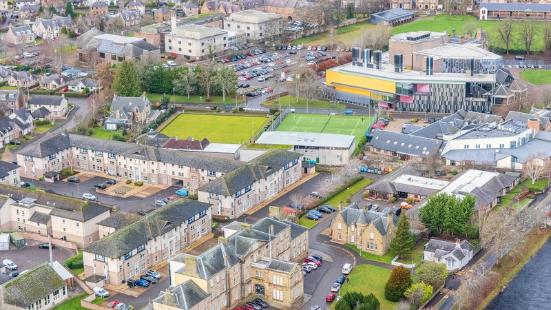 Aerial view of residential neighborhood with historic stone buildings, sports facilities and riverside setting