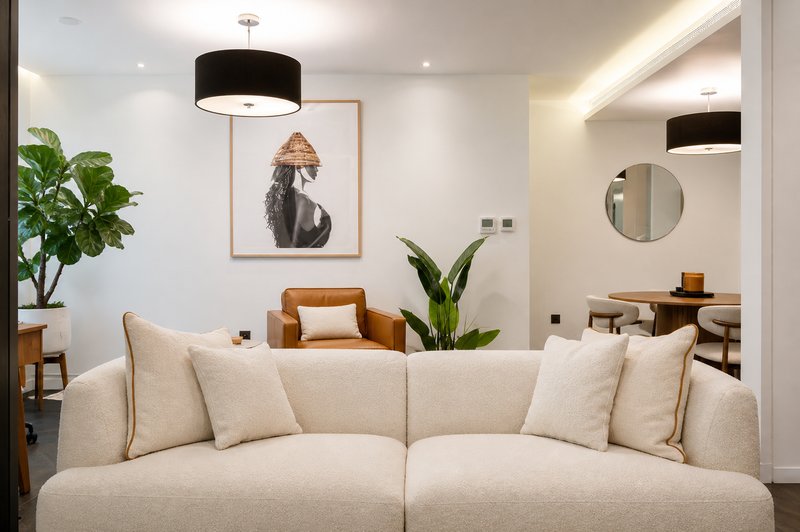 Modern living room with cream sofa, black pendant lights, framed artwork, and potted plants