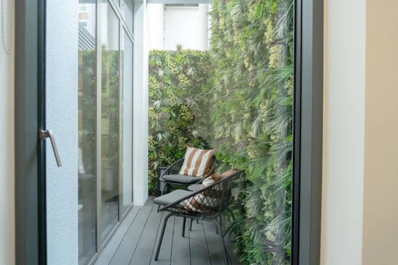 Narrow balcony with chair, striped cushion, and climbing ivy on walls