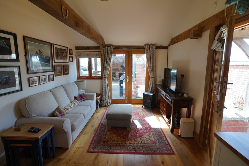 Bright open-plan living room with a large sofa, TV and plenty of natural light, offering small working groups a welcoming space to relax and unwind after a day at work