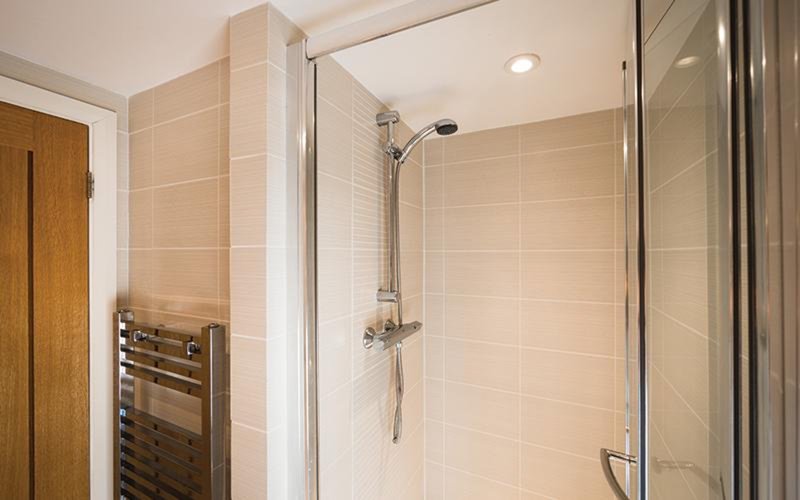 Modern bathroom with walk-in shower, glass enclosure, heated towel rail and cream tile walls