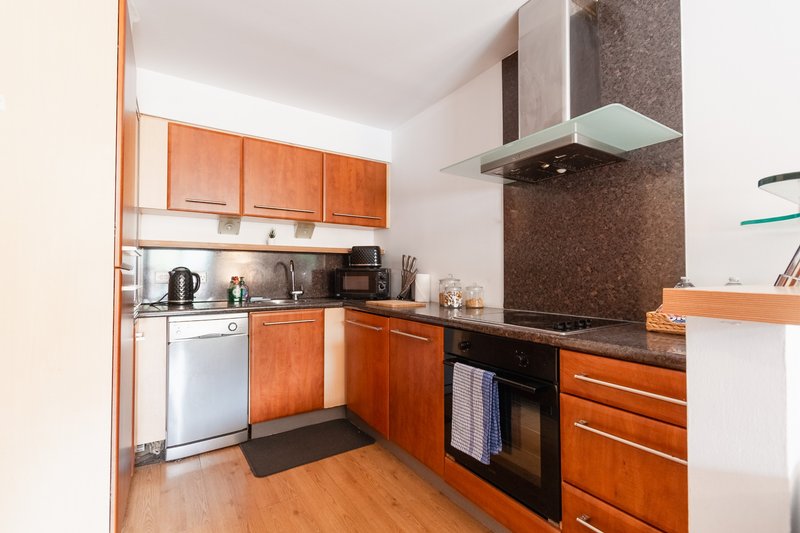 Modern kitchen with orange cabinetry, stainless steel appliances and wooden flooring