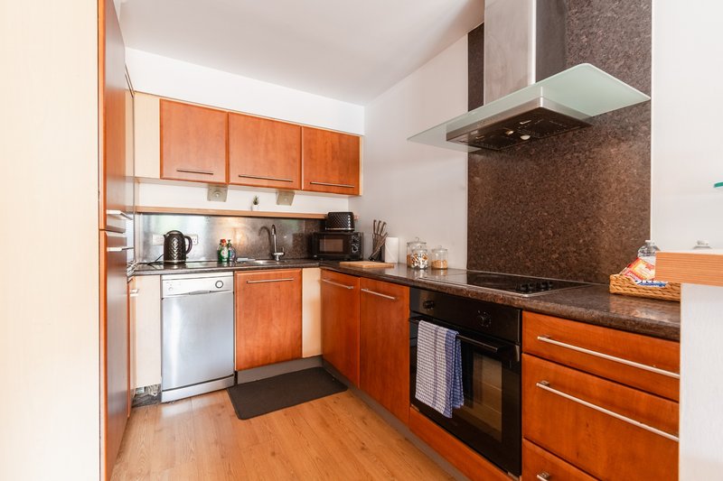 Modern kitchen with orange cabinetry, stainless steel appliances, dark countertop and wooden flooring