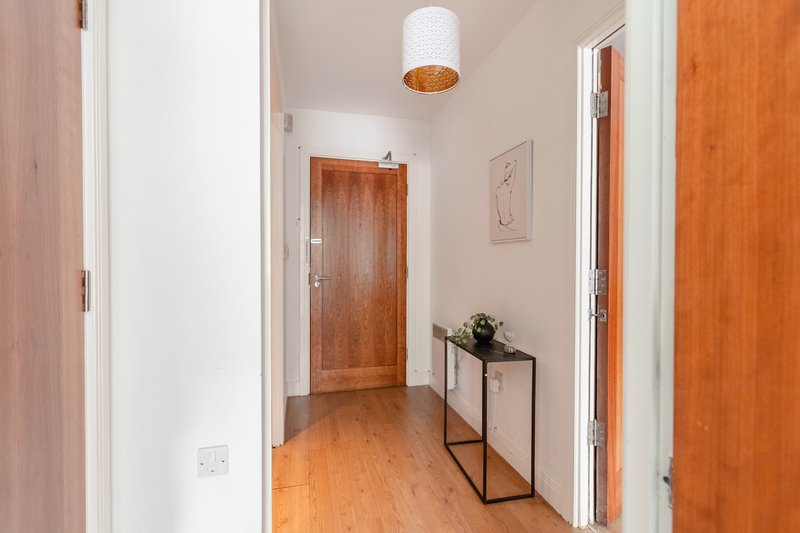 Hallway with wooden doors, pendant light, console table with plant and artwork