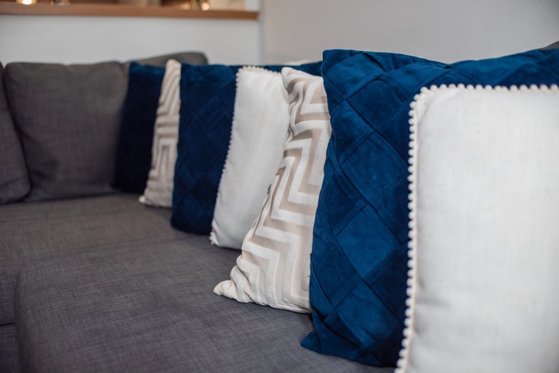 Close-up of sofa with decorative pillows in blue, white, and gray tones