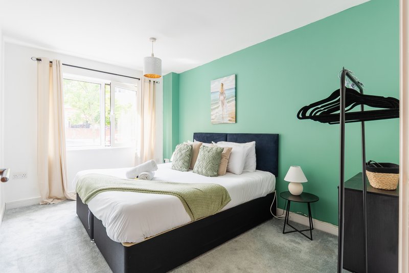 Bright bedroom with black bed, mint green accent wall, and modern furnishings