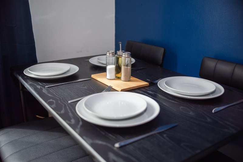 Modern dining table set with white plates, glasses, and wooden serving board