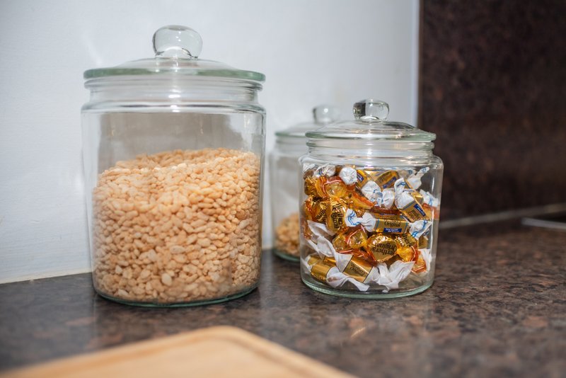 Two glass storage jars on kitchen counter with dried goods and candies