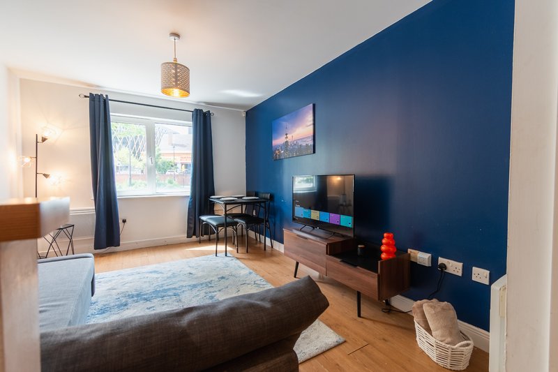 Modern living room with dark blue accent wall, wooden floor, sofa, TV stand and pendant light