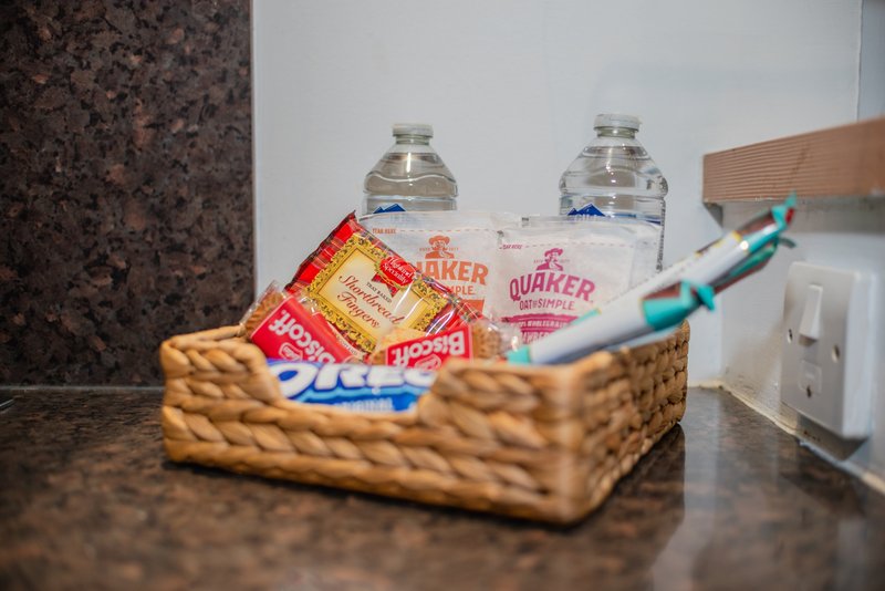 Welcome basket with bottled water, snacks, and toiletries on dark countertop