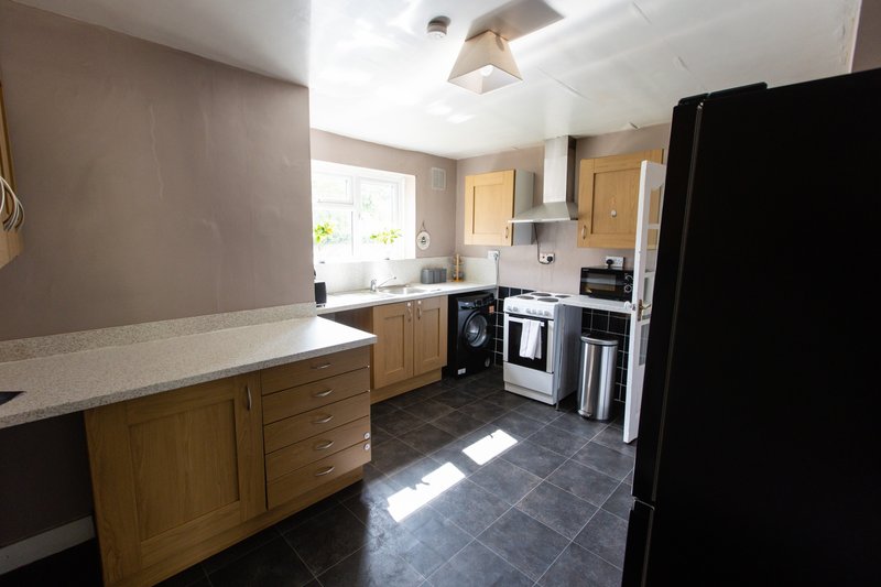 Modern kitchen with wooden cabinets, black appliances, island worktop and tiled flooring
